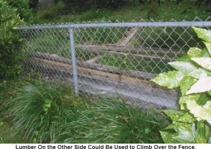 Photo of a fence with lumber behind it. Caption reads: "Lumber On the Other Side Could Be Used to Climb Over the Fence."