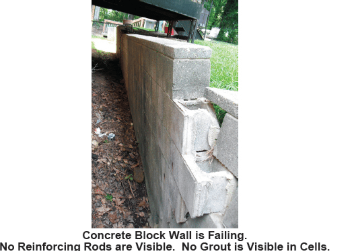Photo depicts a failing concrete block wall with no visible reinforcing rods.